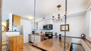 Una cocina con armarios blancos, una mesa de comedor de madera y una araña.