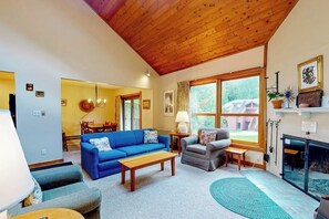 Ein Wohnzimmer mit blauem Sofa, grauem Sessel, Couchtisch aus Holz und Kamin.