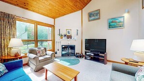Un salon avec un plafond en bois, une cheminée, un téléviseur et un canapé.