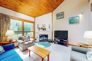 Ein Wohnzimmer mit Holzboden, Kamin, Fernseher und einer Couch.