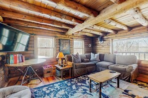 Ein rustikales Blockhaus-Interieur mit einer Couch, einem Couchtisch, einer Lampe und einem Fernseher.
