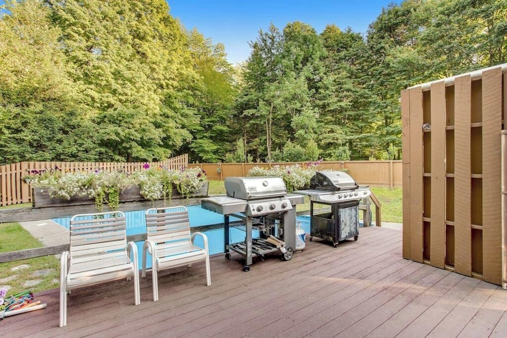 En trädgård med en pool, två trädgårdsstolar, en grill och en utegrill.