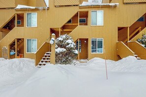 Ein mehrstöckiges Holzgebäude mit Balkonen und einer Treppe, bedeckt mit Schnee.