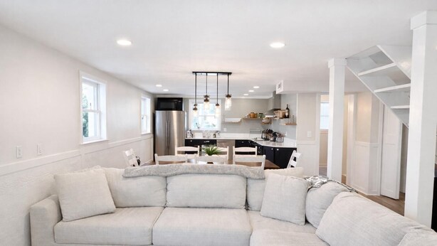 Una sala moderna con un sofá modular, un comedor y una cocina con isla integrada.