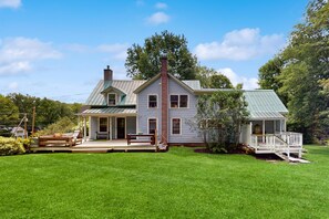 A two-story house with a porch, a covered deck, and a well-maintained lawn.