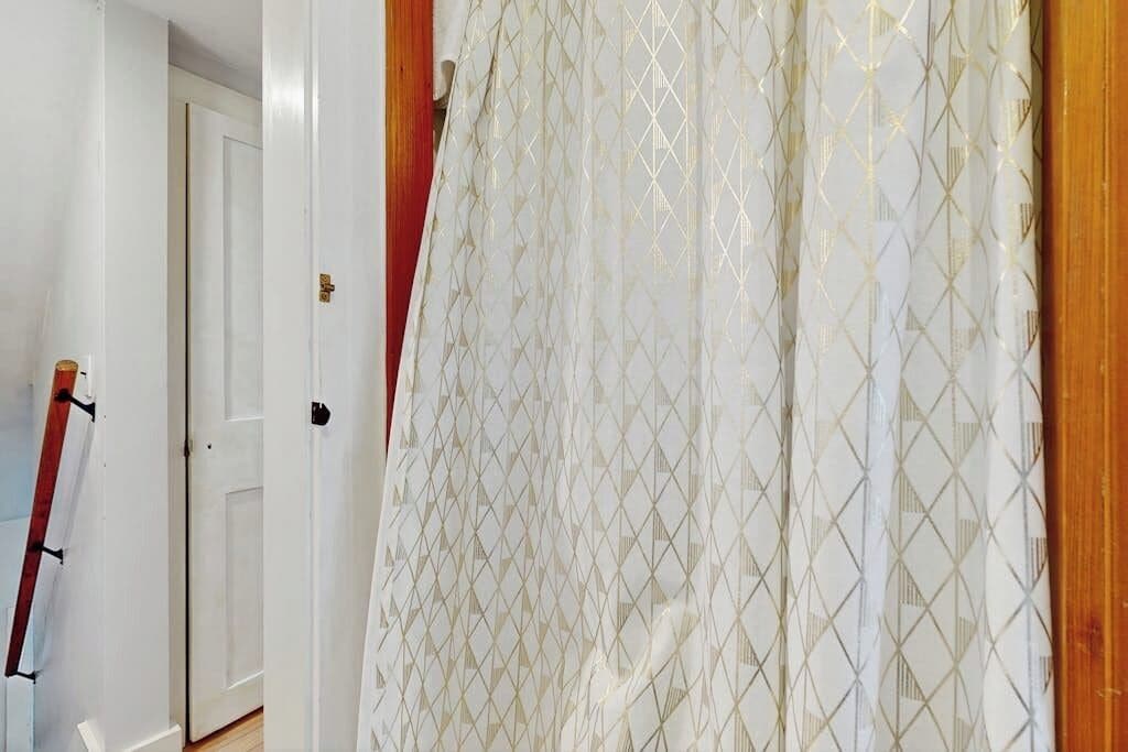 A room with a white door, a patterned curtain, and a wooden door frame.