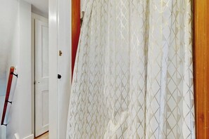 A room with a white door, a patterned curtain, and a wooden door frame. - Cozy updated apartment: near skiing, hiking, shops & dining (Waterbury)