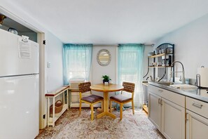 A compact kitchen with a dining area, a refrigerator, a coffee machine, and a sink. - Cozy updated apartment: near skiing, hiking, shops & dining (Waterbury)