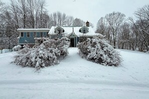 A house with a snow-covered roof, surrounded by snow-covered trees and bushes. - Cozy updated apartment: near skiing, hiking, shops & dining (Waterbury)