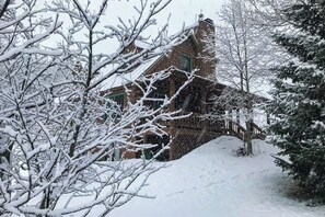 Ein schneebedecktes Gebäude mit Ziegelaußenwand und einer Holztreppe, die zu einer Veranda führt.