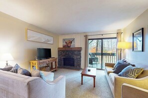 A living room with a fireplace, a television, a sofa, and a table.