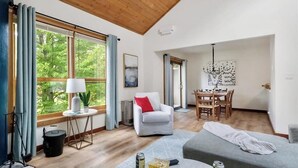 A spacious living area with a large window, a dining table, and a cozy seating arrangement. - Ski-in/shuttle-out condo w/WiFi, fireplace, balcony, & newly renovated kitchen (Killington)
