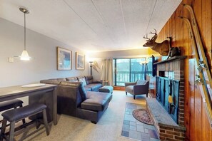 A cozy living room with a fireplace, a sofa, a dining area, and a mounted deer head. - High-floor resort condo with free WiFi and full kitchen - walk to lifts (Killington)