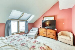 A bedroom with a bed, a dresser, a TV, and a chair. - Ski-in/out condo with  pool, hot tub, sauna & fast WiFi (Killington)