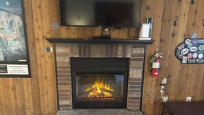 A fireplace with a TV above it, a fire extinguisher, and a wall with a map and stickers. - Resort condo with mountain views, full kitchen, and free WiFi (Killington)