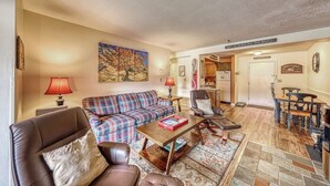A living room with a sofa, armchairs, a coffee table, and a dining area with a table and chairs. - Resort condo with mountain views, full kitchen, and free WiFi (Killington)