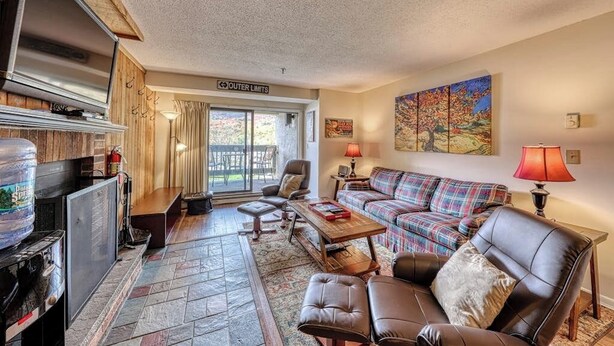 A living room with a fireplace, a sofa, a coffee table, and a television. - Resort condo with mountain views, full kitchen, and free WiFi (Killington)