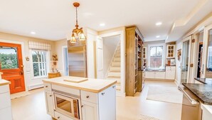 Una cocina con una isla central, una escalera y vistas al exterior.
