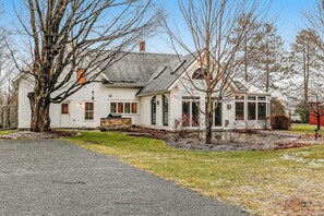 A white house with a covered porch, a stone fireplace, and a garage.