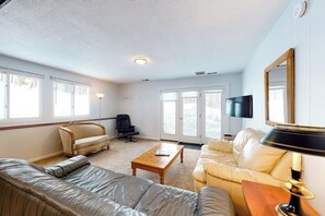 Ein Wohnzimmer mit einer Couch, einem Sessel, einem Couchtisch und einem Fernseher.