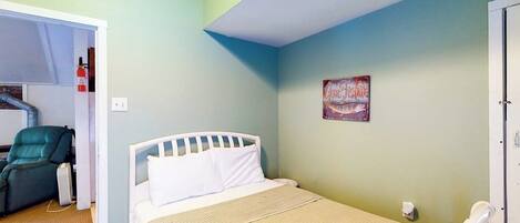 Un dormitorio con una cama, una silla, un reloj de pared y un cartel.
