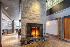Ein Kamin aus Stein mit Feuer, Holzboden und hohe Decke.