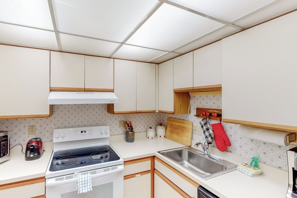 Una cucina funzionale con piano cottura, lavello e pensili in legno.