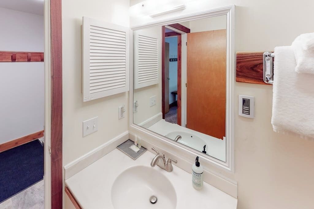 Un baño con un lavabo blanco, un espejo y un perchero para toallas.