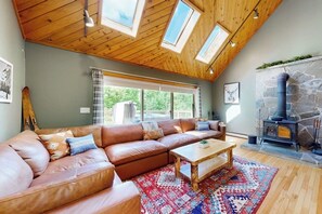 Ein gemütliches Wohnzimmer mit einer ledernen Eckcouch, einem Holztisch und einem Kamin aus Stein.