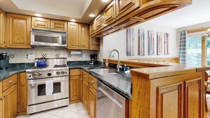 A kitchen with wooden cabinets, a microwave, a stove, and a dishwasher. - 3-story secluded home with private sauna, hot tub, pond on-site (Killington)
