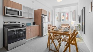 A modern kitchen with stainless steel appliances, wooden cabinets, and a dining area with a table set for four. - Bellavista Galleria | Old San Juan (San Juan)