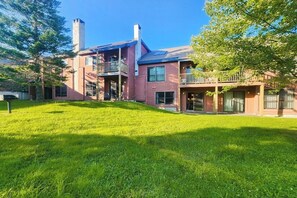 Ein zweistöckiges Haus mit Veranda, überdachter Terrasse und großem Vorgarten.