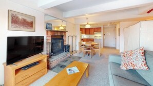 Una sala de estar con televisión, chimenea, comedor y cocina.