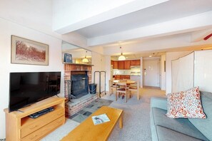 A living room with a TV, fireplace, dining area, and kitchen. - 5th-floor mountain-view condo, easy access to the slopes free shuttle or walk (Killington)