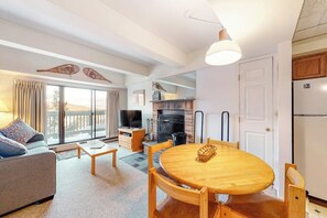 A living room with a sofa, a coffee table, a dining table with chairs, a fireplace, and a television. - 5th-floor mountain-view condo, easy access to the slopes free shuttle or walk (Killington)