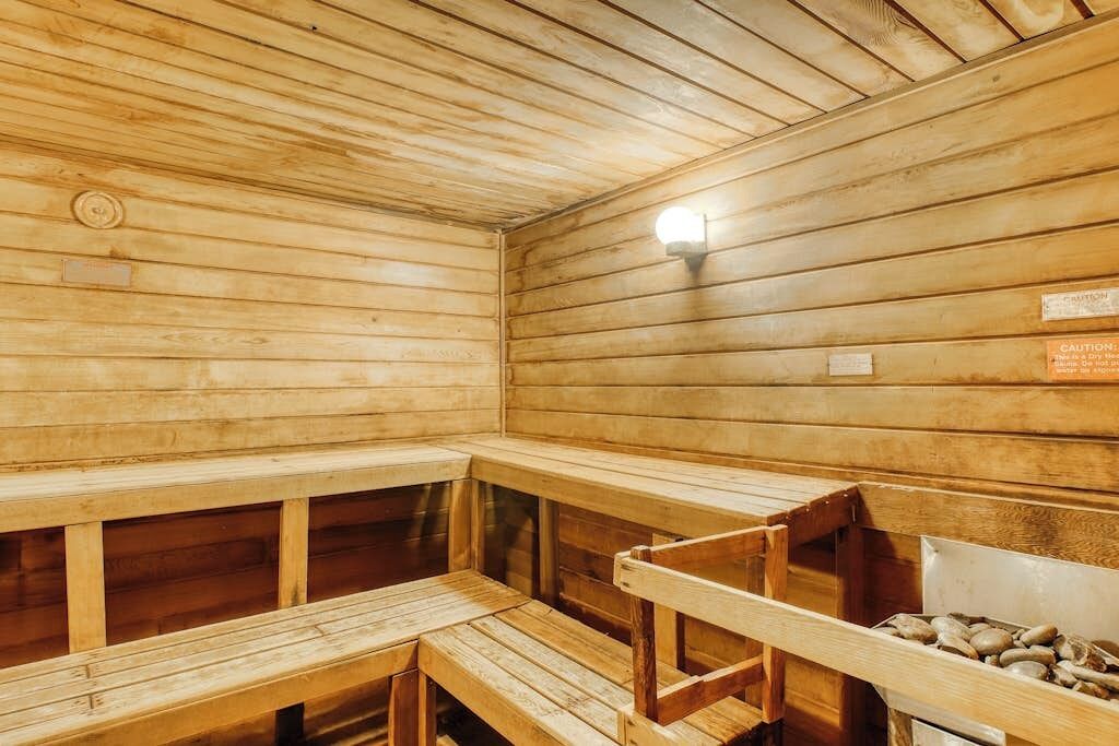 A wooden sauna with benches and a wall-mounted light fixture.