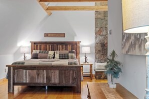 Ein Schlafzimmer mit einem hölzernen Bett, zwei Nachttischlampen, einer Steinwand und einer kleinen Zimmerpflanze.