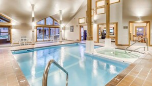 An indoor swimming pool with clear water, a diving board, and a separate hot tub area. - Two-story condo with private sauna, pool, hot tubs & gym - walk to lifts (Killington)