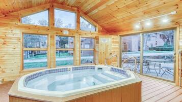 Une cabane en bois dotée d’un bain à remous, de grandes fenêtres et d’une terrasse.