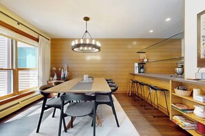 A modern kitchen with a wooden countertop, bar stools, and a hanging light fixture. - Two-story condo with private sauna, pool, hot tubs & gym - walk to lifts (Killington)