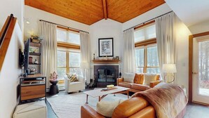 A cozy living room with a fireplace, leather sofas, a coffee table, and a bookshelf. - Two-story condo with private sauna, pool, hot tubs & gym - walk to lifts (Killington)