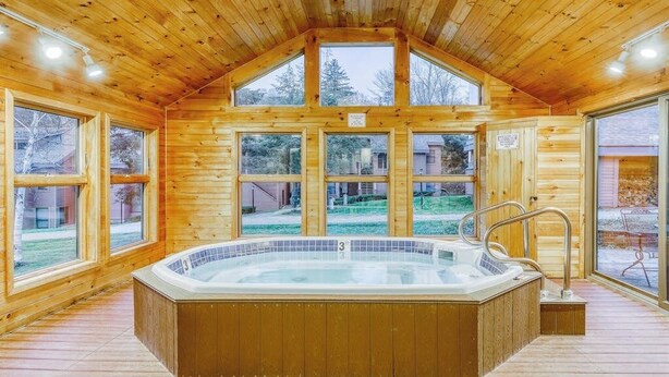 Una baita in legno con idromassaggio, ampie finestre e vista sulla natura.