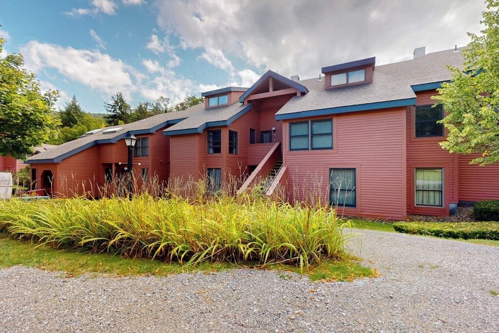 A red building with multiple windows and a gravel driveway.