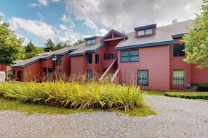 A red building with multiple windows and a gravel driveway. - Trail Creek 75 | Condo in Killington (Killington)