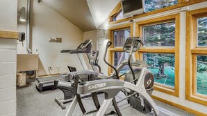 Una palestra con tapis roulant e cyclette, ampie finestre e un televisore.