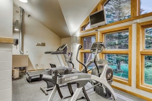 A gym with treadmills and a stationary bike, large windows, and a TV. - Trail Creek 75 | Condo in Killington (Killington)