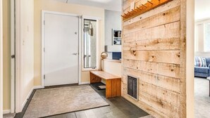 A hallway with a wooden wall, a bench, a door, and a small table with a basket. - Welcoming Condo with Shared Pools, Easy Access to Golf & Slopes (Warren)