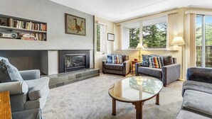 A living room with a fireplace, sofas, a coffee table, and a bookshelf. - Welcoming Condo with Shared Pools, Easy Access to Golf & Slopes (Warren)