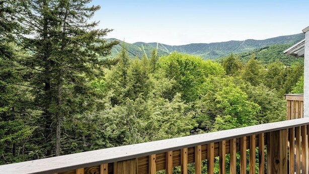 A wooden deck with a view of a forested mountain range. - Welcoming Condo with Shared Pools, Easy Access to Golf & Slopes (Warren)