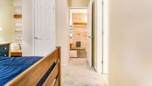 A bedroom with a wooden bed, a white door, and a hallway leading to a wooden wall. - Welcoming Condo with Shared Pools, Easy Access to Golf & Slopes (Warren)